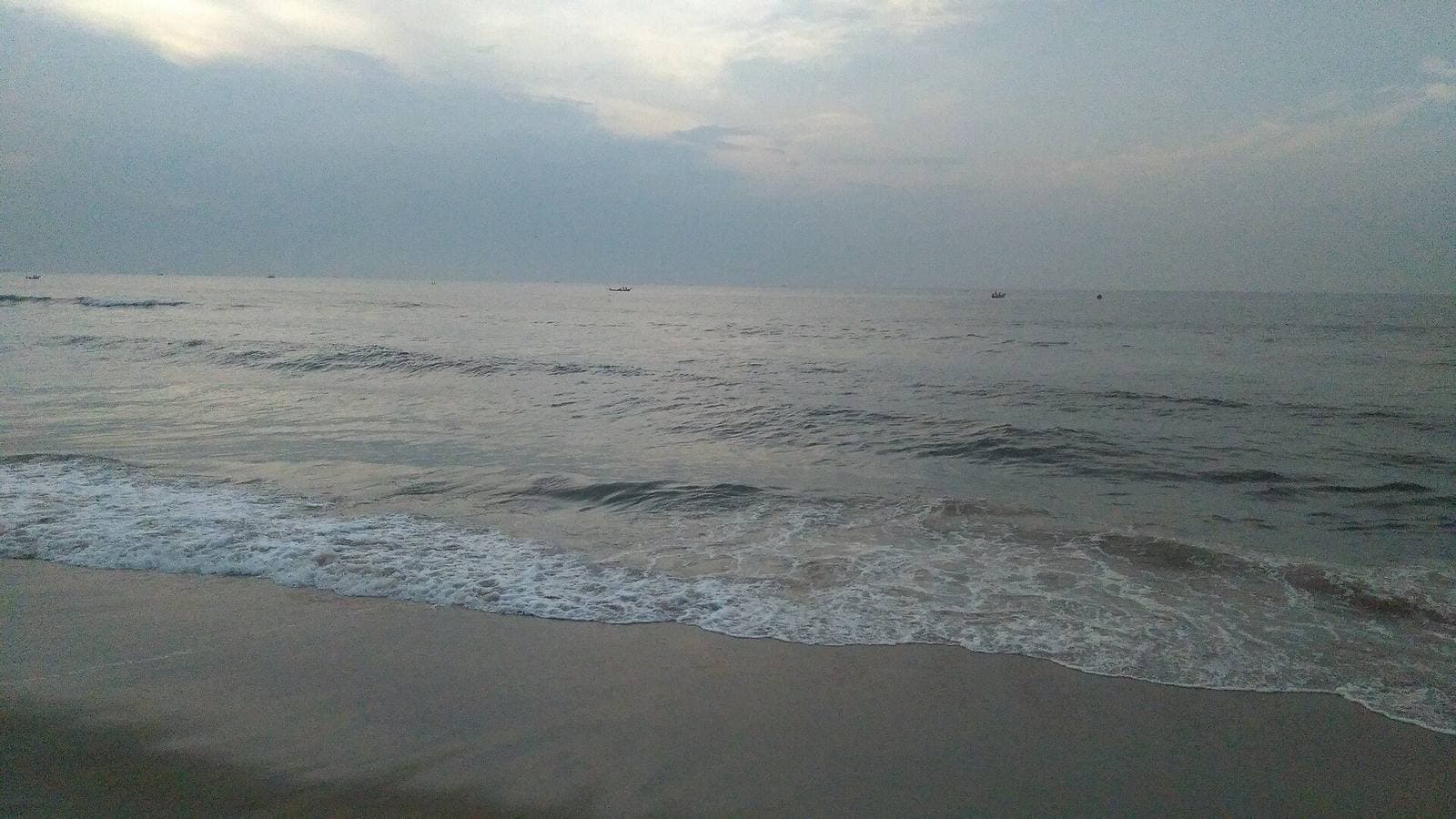 Waves on the shore of Marina Beach, Chennai, under a cloudy sky